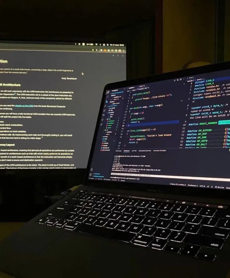 A laptop on a desk displaying source code in a dark-themed editor.