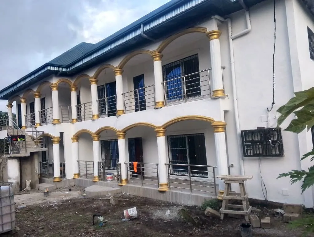 A newly finished two-storey building with arched balconies, white columns with gold capitals and steel railings.